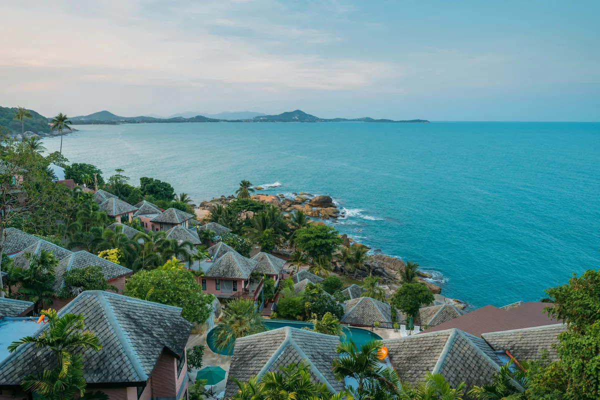 Uitzicht over de kust van Koh Samui met resortdaken tussen tropisch groen.
