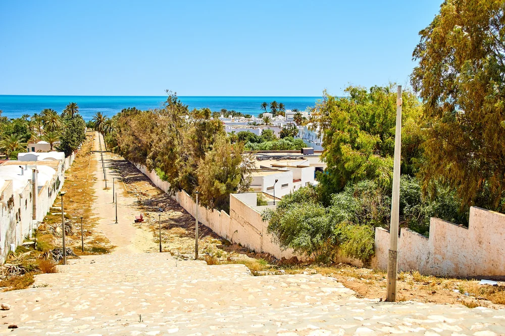Straat met palmbomen en uitzicht op zee bij Sousse.