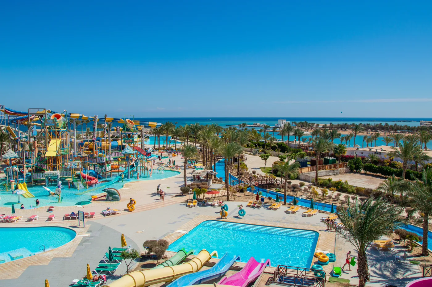 Strand met rieten parasols en palmbomen aan de turquoise Rode Zee in Hurghada