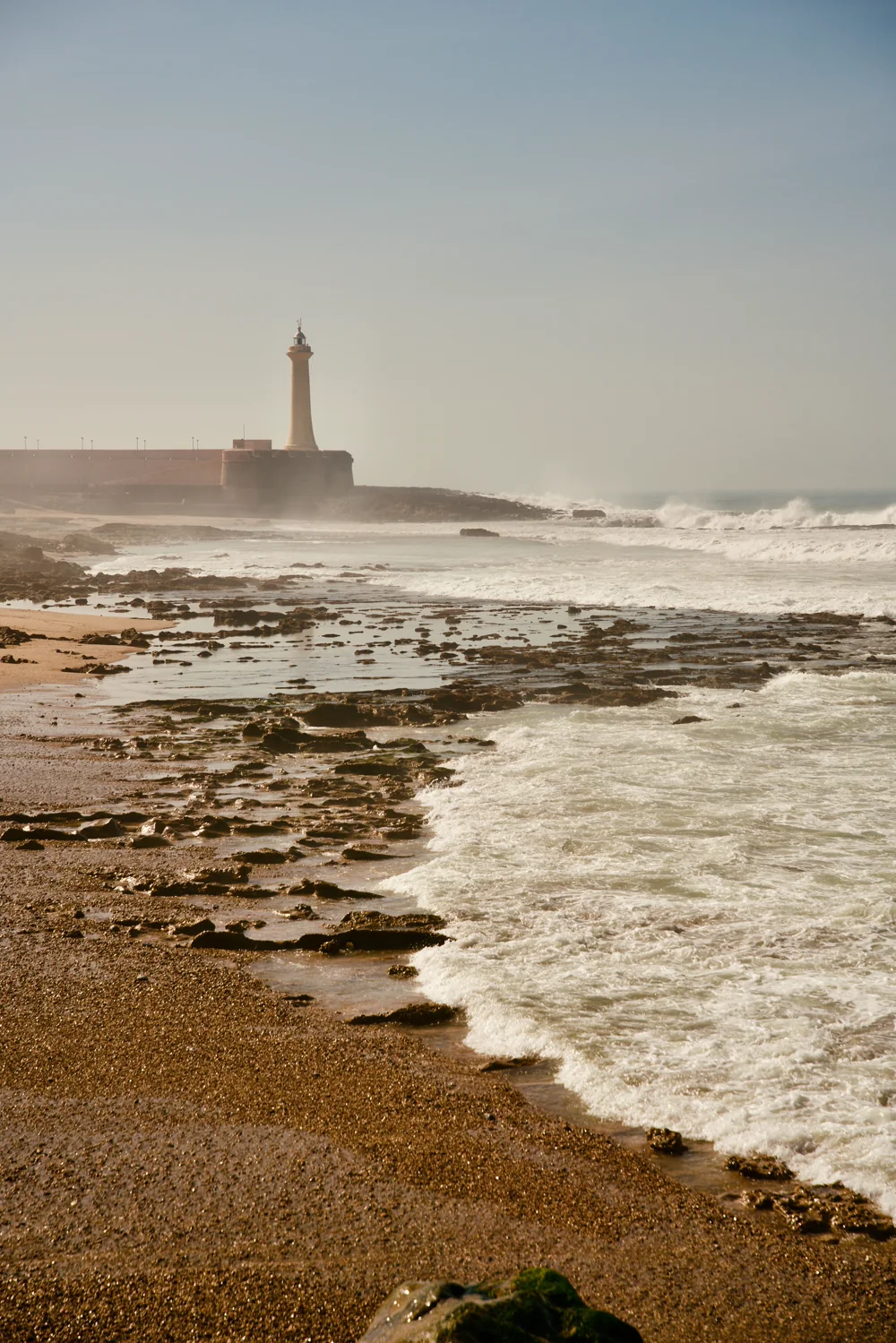 Vuurtoren aan de kust bij Rabat met rotsen en aanrollende golven