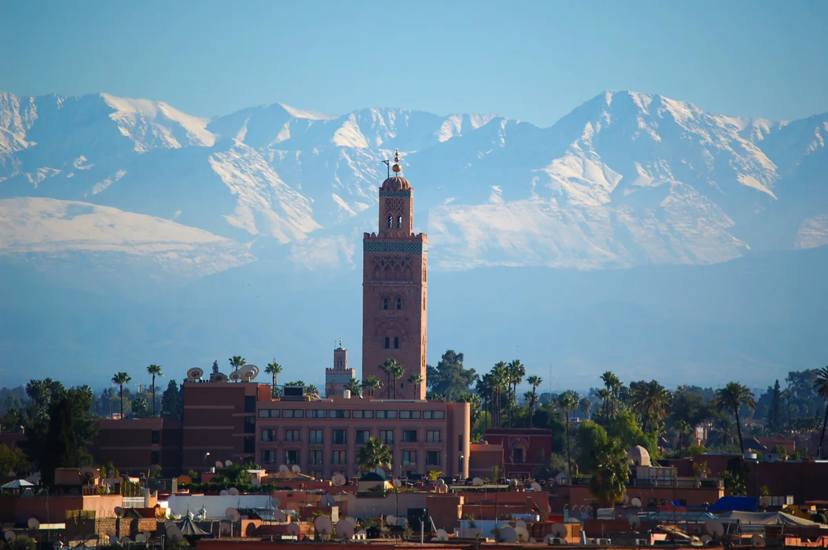 De Koutoubia-minaret in Marrakech met palmbomen en de besneeuwde Atlas op de achtergrond