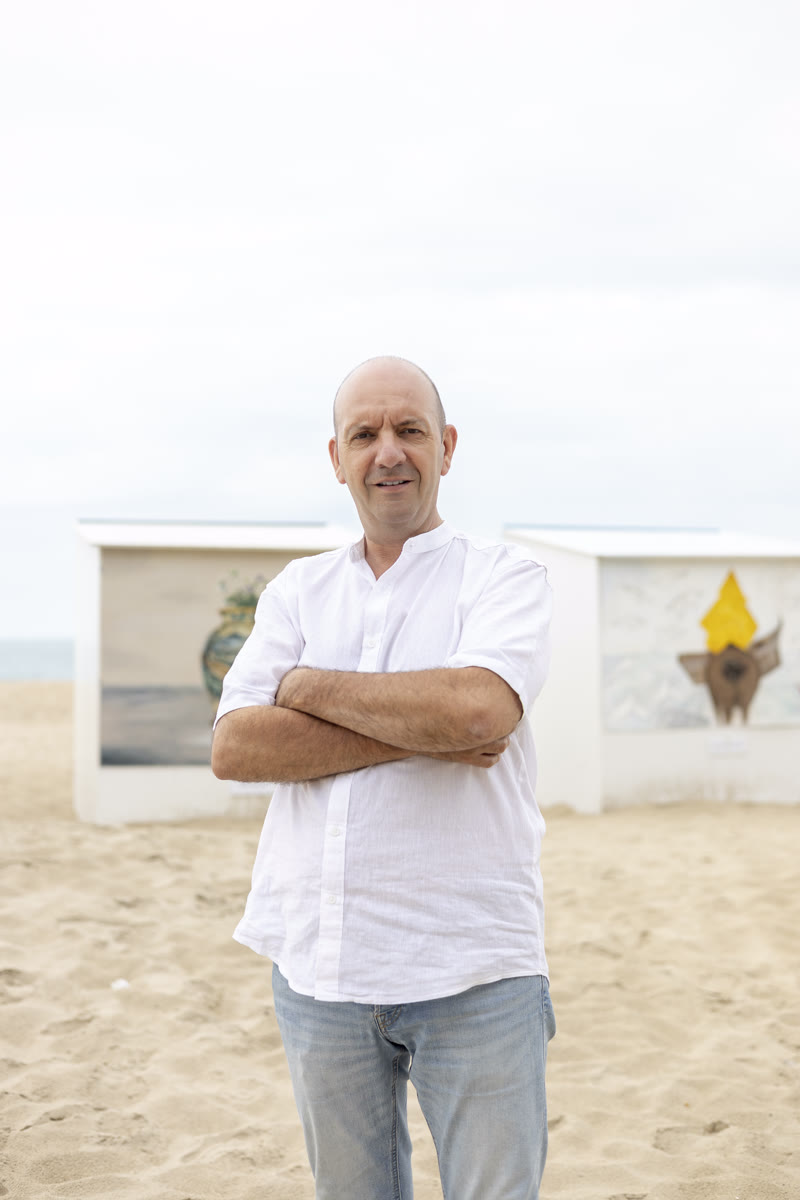 Olivier van Sea Breeze Reizen op het strand van De Panne, met beschilderde strandcabines op de achtergrond.