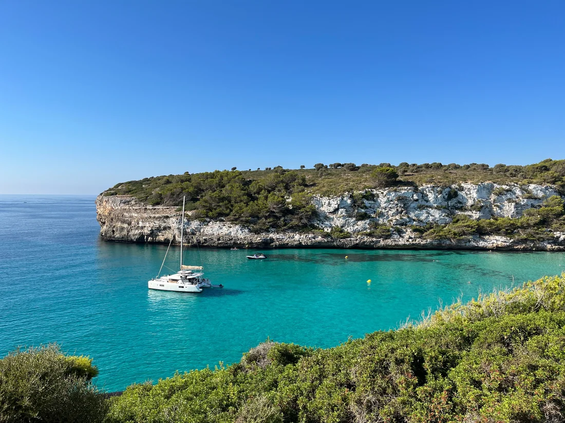 Zeilboot in een turquoise baai omringd door kliffen op de Balearen.
