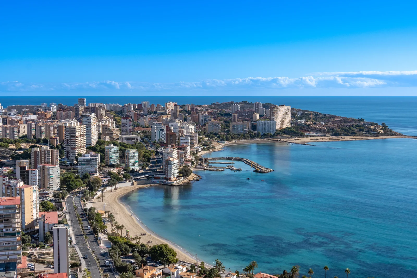 Luchtfoto van een Spaanse kustplaats met appartementsgebouwen langs een baai met strand