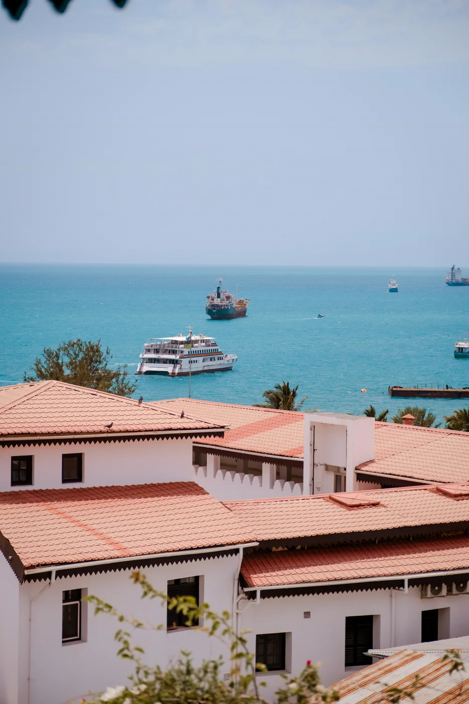 Uitzicht over rode pannendaken van Stone Town, met schepen op zee op de achtergrond