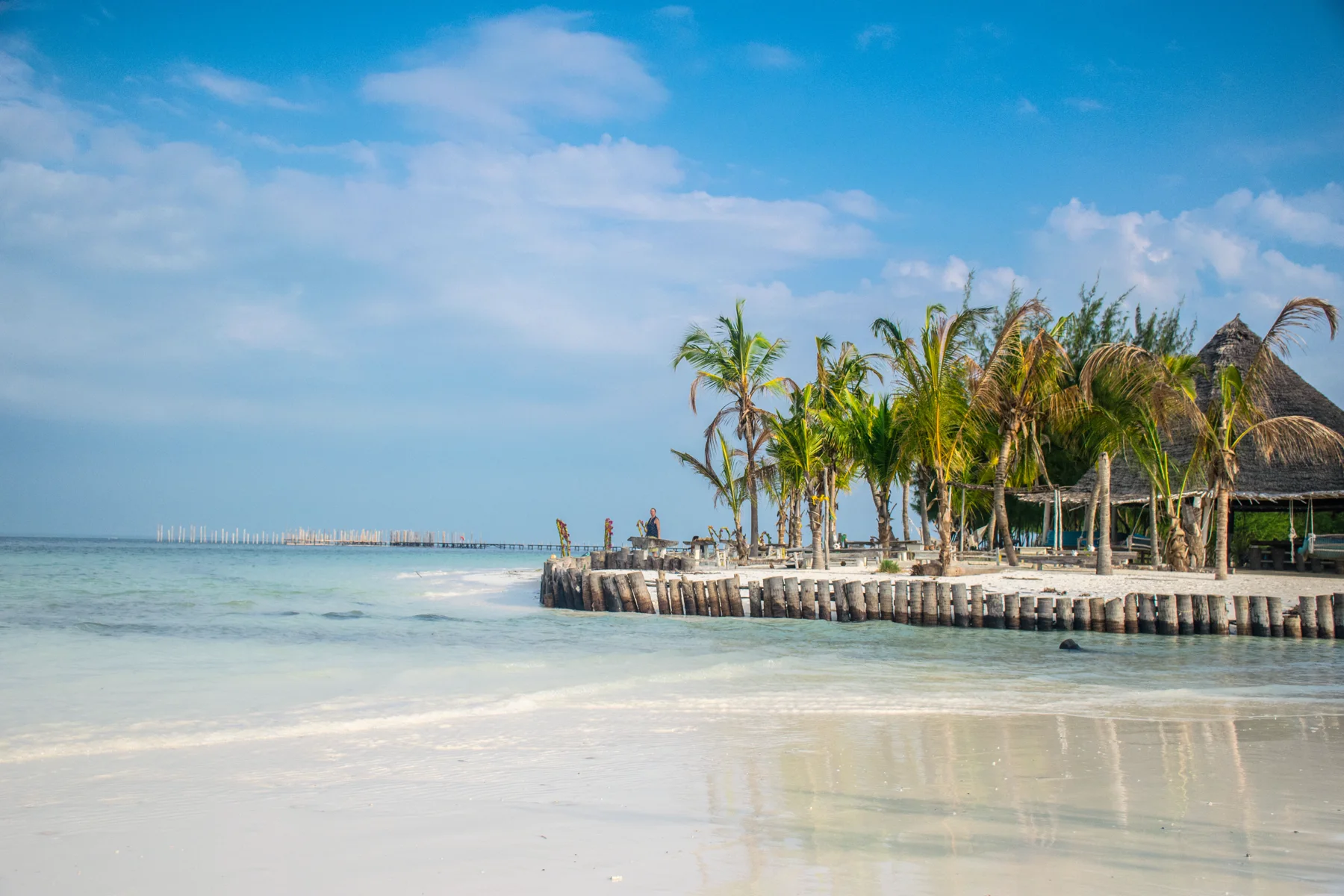 Wit zandstrand met palmbomen en een rieten strandpaviljoen langs de turquoise Indische Oceaan